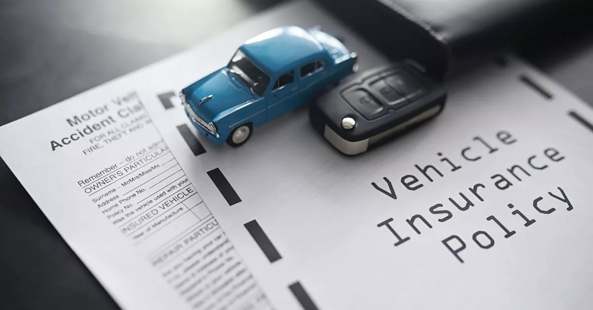 Vehicle insurance policy paperwork with car keys and model car symbolizing what to do when the other driver is uninsured in Oregon.