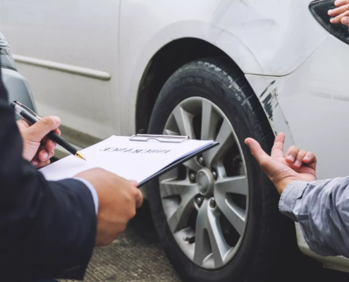 Insurance adjuster inspecting car damage and taking notes after a collision showing what to do if the other driver is uninsured in Oregon.