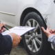 Insurance adjuster inspecting car damage and taking notes after a collision showing what to do if the other driver is uninsured in Oregon.