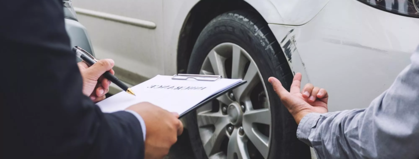 Insurance adjuster inspecting car damage and taking notes after a collision showing what to do if the other driver is uninsured in Oregon.