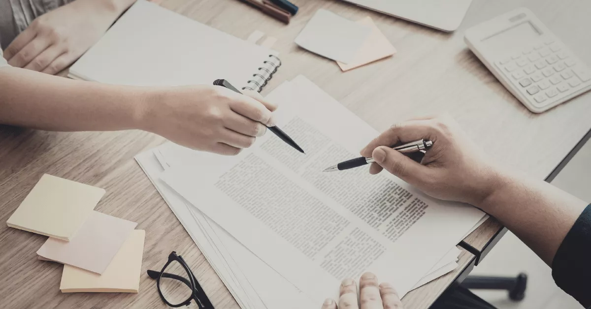Two people reviewing and pointing at legal documents on a desk during a Portland hit and run lawyer consultation.