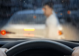 View from inside a car during heavy rain as a person stands near a vehicle ahead after a crash, immediately calling a portland hit and run lawyer.