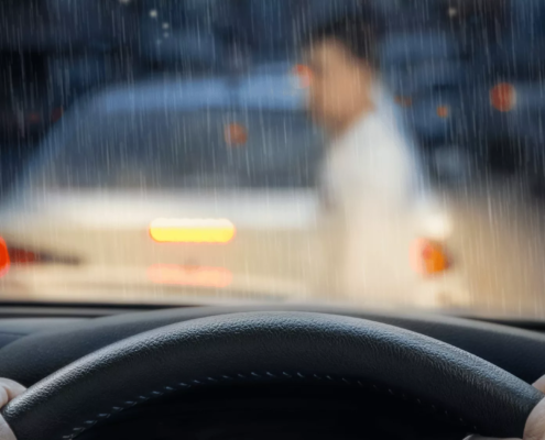 View from inside a car during heavy rain as a person stands near a vehicle ahead after a crash, immediately calling a portland hit and run lawyer.