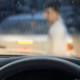 View from inside a car during heavy rain as a person stands near a vehicle ahead after a crash, immediately calling a portland hit and run lawyer.