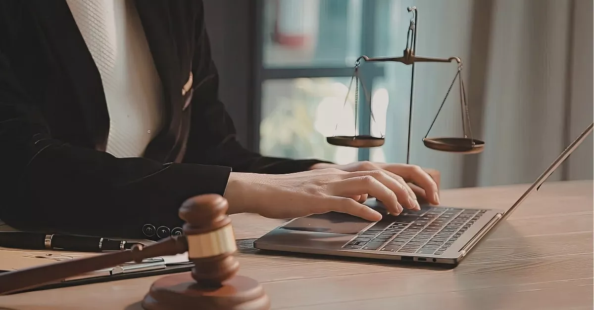 Personal injury lawyer working on an underinsured motorist case with scales of justice and laptop in office.