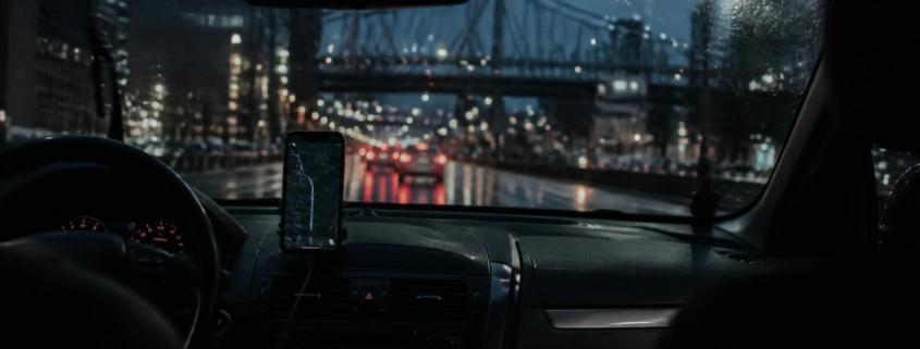 Night view from inside a Portland Uber, phone mounted on the dash and wet street ahead.